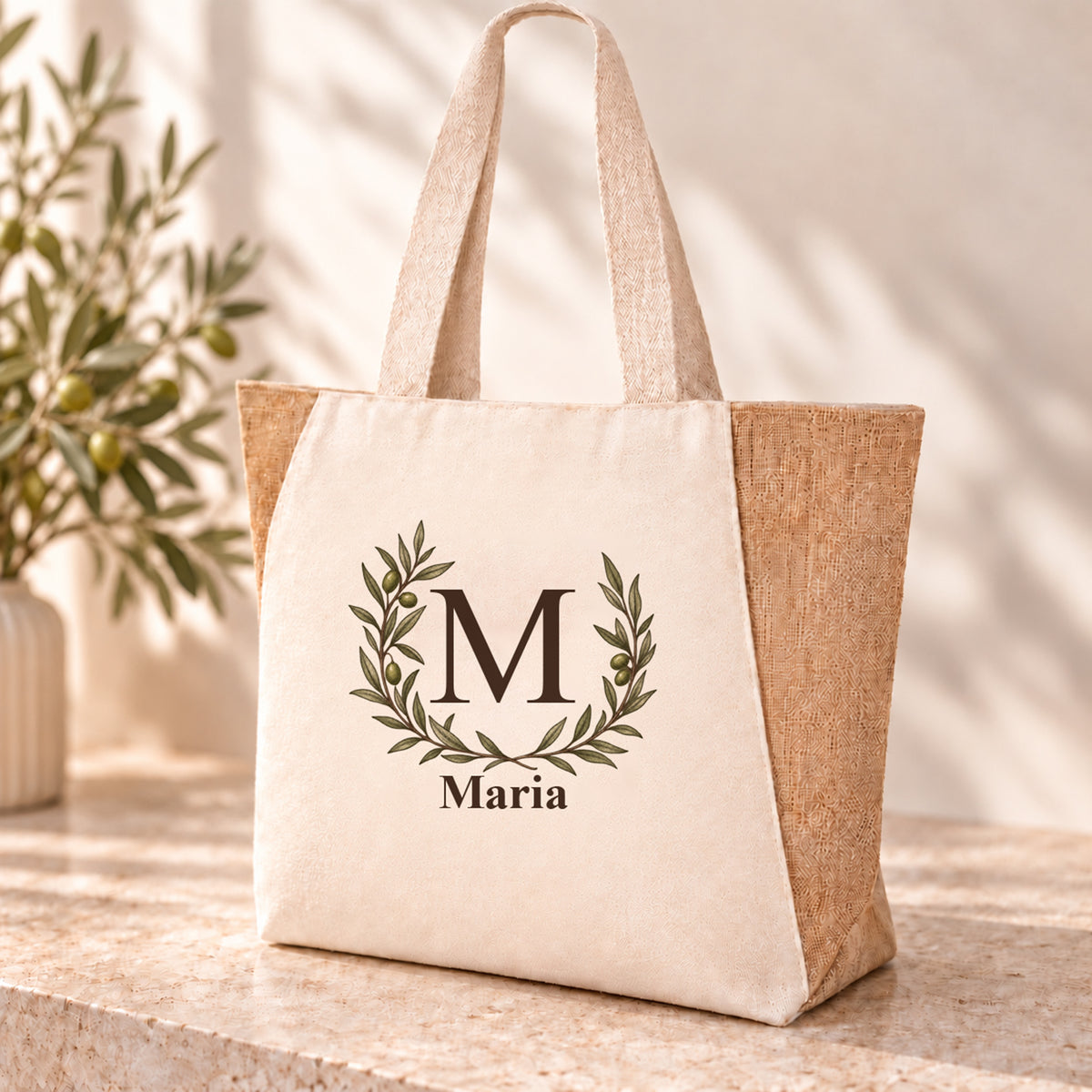 Personalisierter Shopper mit offenem Olivenkranz, Initial und Wunschname auf naturfarbener Front.