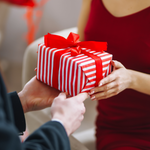 Geschenk in rot-weißem Streifenpapier mit rotem Band.