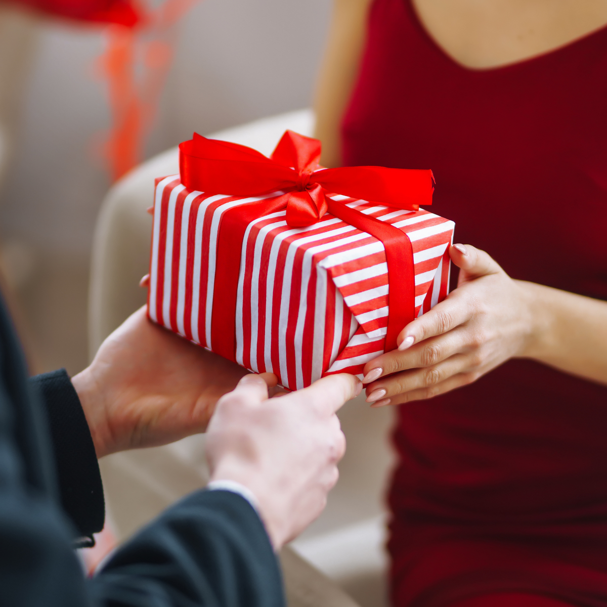 Geschenk in rot-weißem Streifenpapier mit rotem Band.