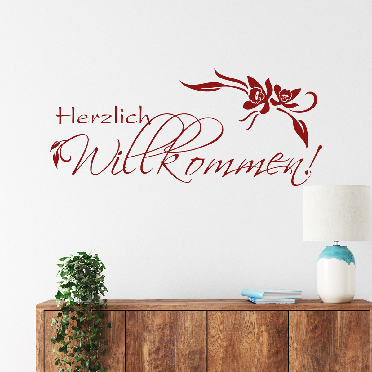 Rote Wanddekoration mit "Herzlich Willkommen!" und Blumenmotiven.
